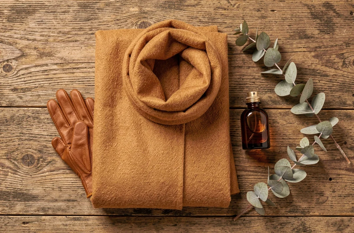 Flatlay d'accessoires de mode automne en camel, cognac et cachemire sur une surface en bois, représentant les couleurs tendance de la saison